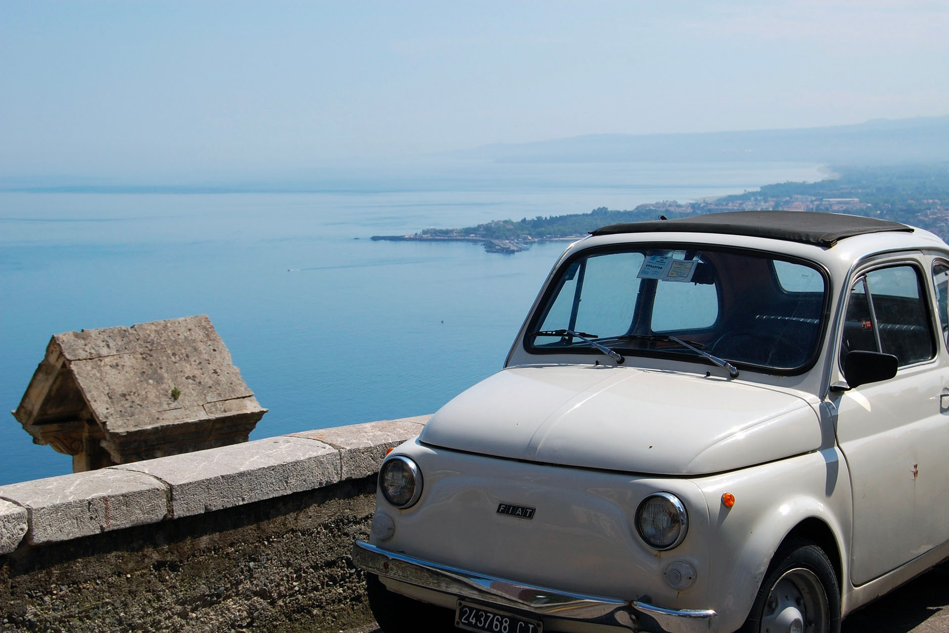 vintage white fiat 500 with view of the Sicilian coast